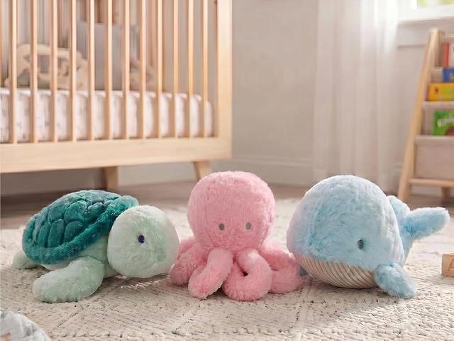 Snuggle Buddies whale, turtle and octopus by a cot